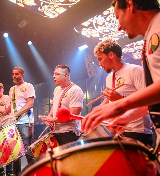 Grupo de percussão tocando tambores coloridos no salão