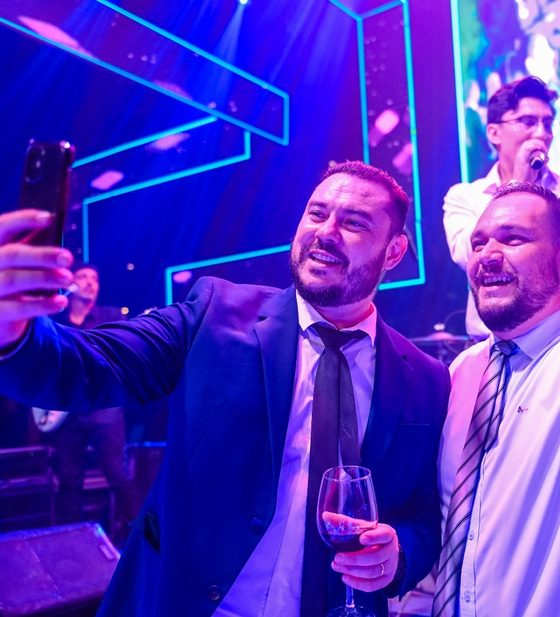 Convidados tirando uma selfie no palco, com o cantor ao fundo